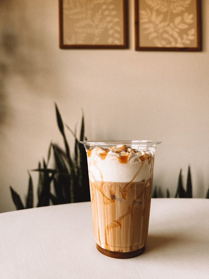 Close-up of a delicious iced caramel coffee topped with whipped cream on a café table.